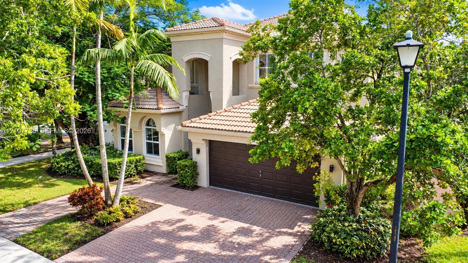 15606 SW 52nd Court, Miramar, FL 33027 Stucco exterior featuring arched windows, a multi-paneled garage door, a tile roof, and a paved stone driveway