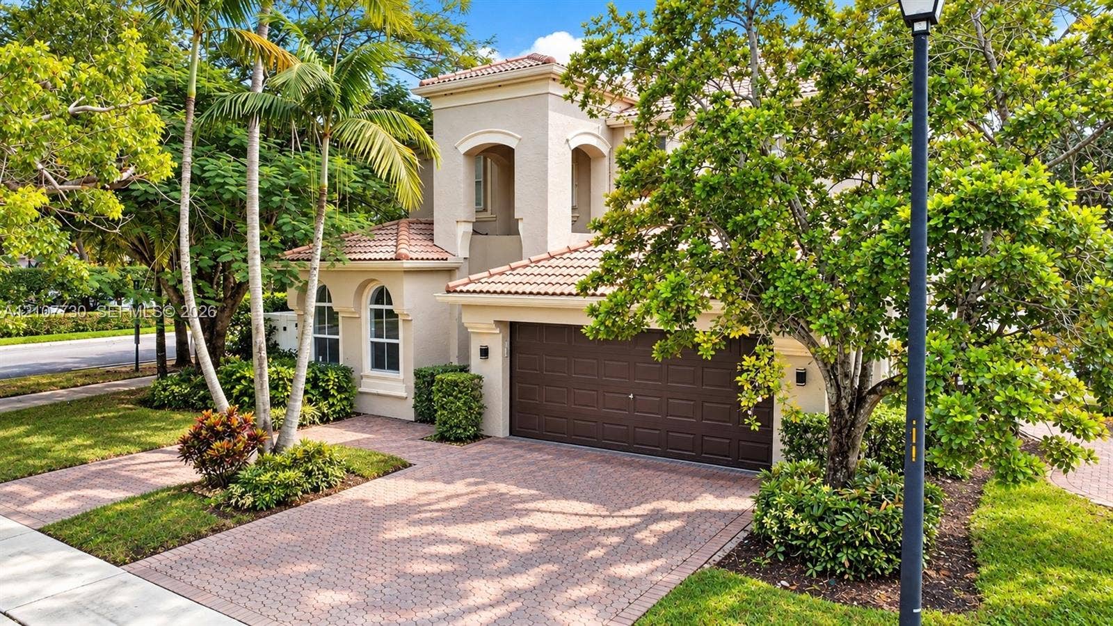 15606 SW 52nd Court, Miramar, FL 33027 Stucco exterior featuring arched windows, a multi-tiered tile roof, and a paved driveway leading to an attached two-car garage