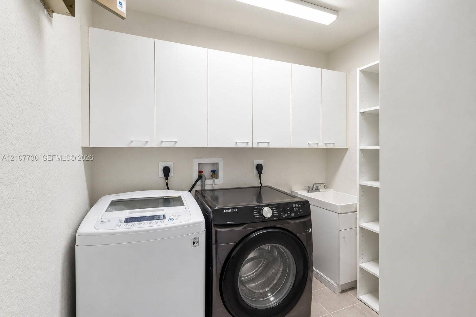 15606 SW 52nd Court, Miramar, FL 33027 Laundry room featuring white wall-mounted cabinetry, integrated open shelving, a utility sink with white vanity base, and overhead lighting