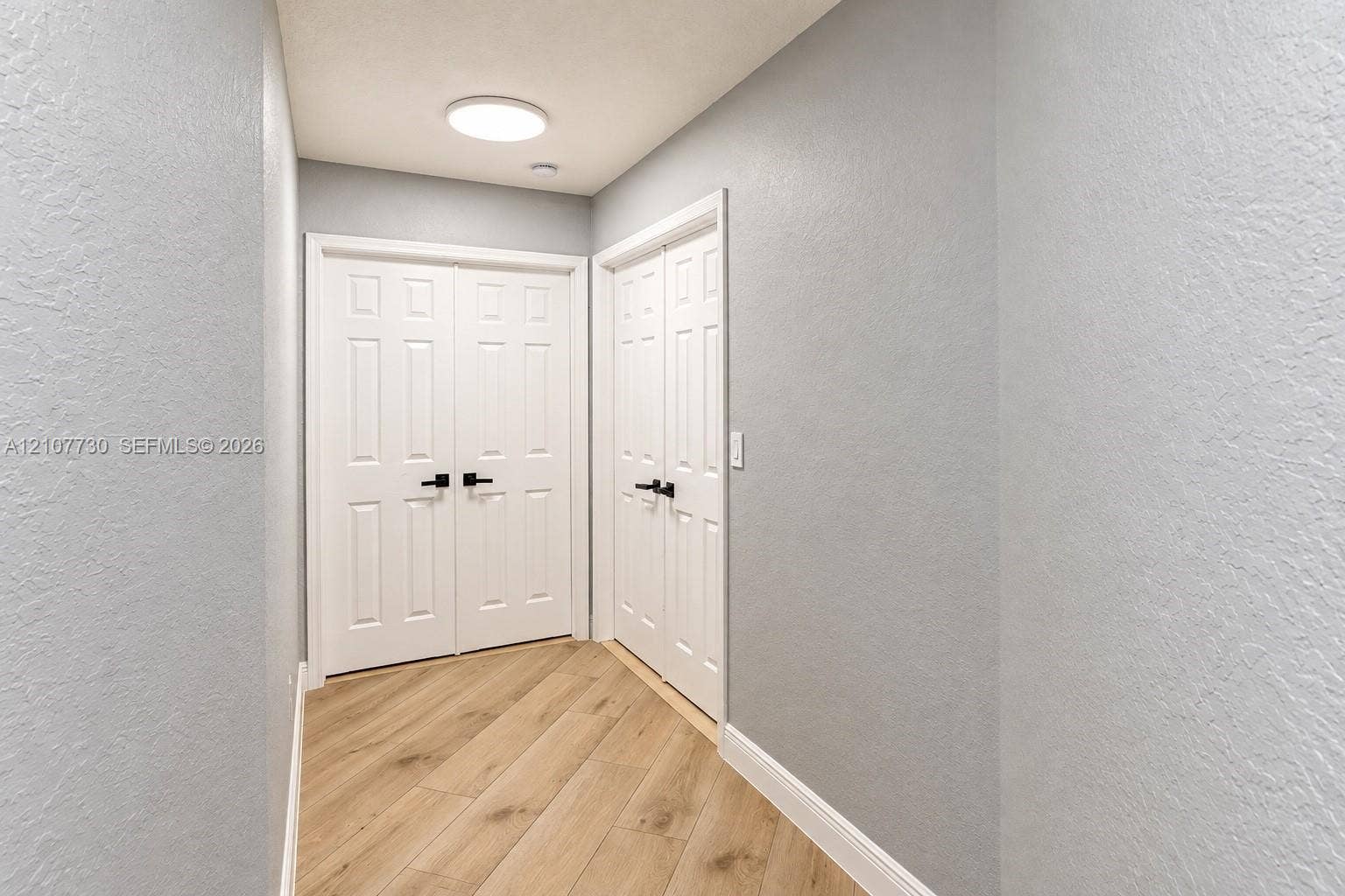 15606 SW 52nd Court, Miramar, FL 33027 Wood-finish flooring, light gray walls, white six-panel double doors, and matte black hardware