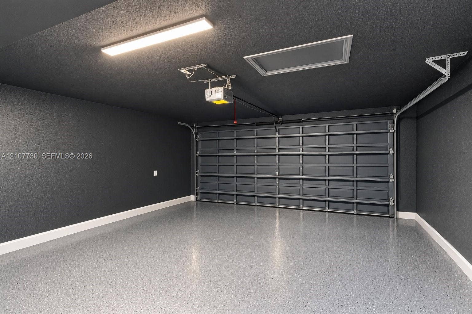 15606 SW 52nd Court, Miramar, FL 33027 Finished garage space featuring dark-toned walls, a sectional metal garage door, epoxy-coated flooring, and an integrated ceiling light fixture