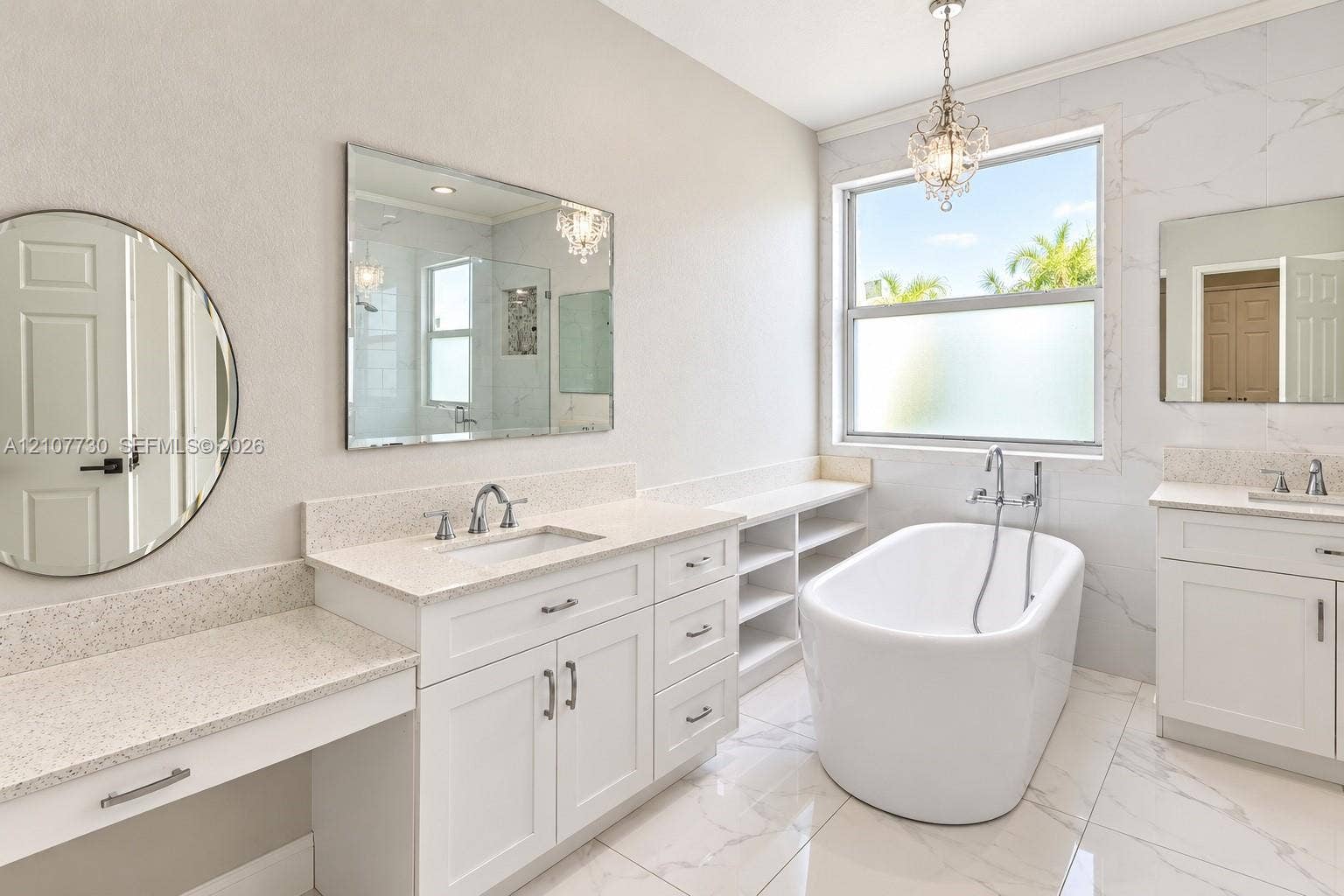 15606 SW 52nd Court, Miramar, FL 33027 Freestanding soaking tub with chrome wall-mounted faucet, dual white vanities with stone countertops, integrated open shelving, and large-format tile flooring