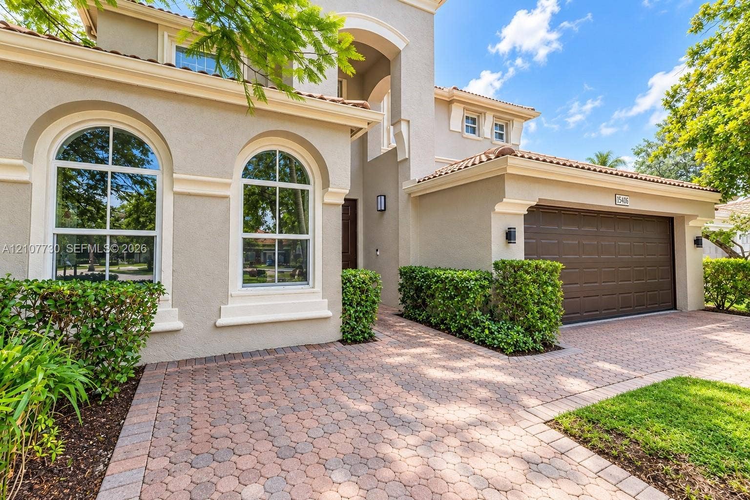 15606 SW 52nd Court, Miramar, FL 33027 Mediterranean-style exterior featuring a paved stone driveway, arched multi-pane windows, decorative trim accents, a tile roof, and an attached multi-car garage