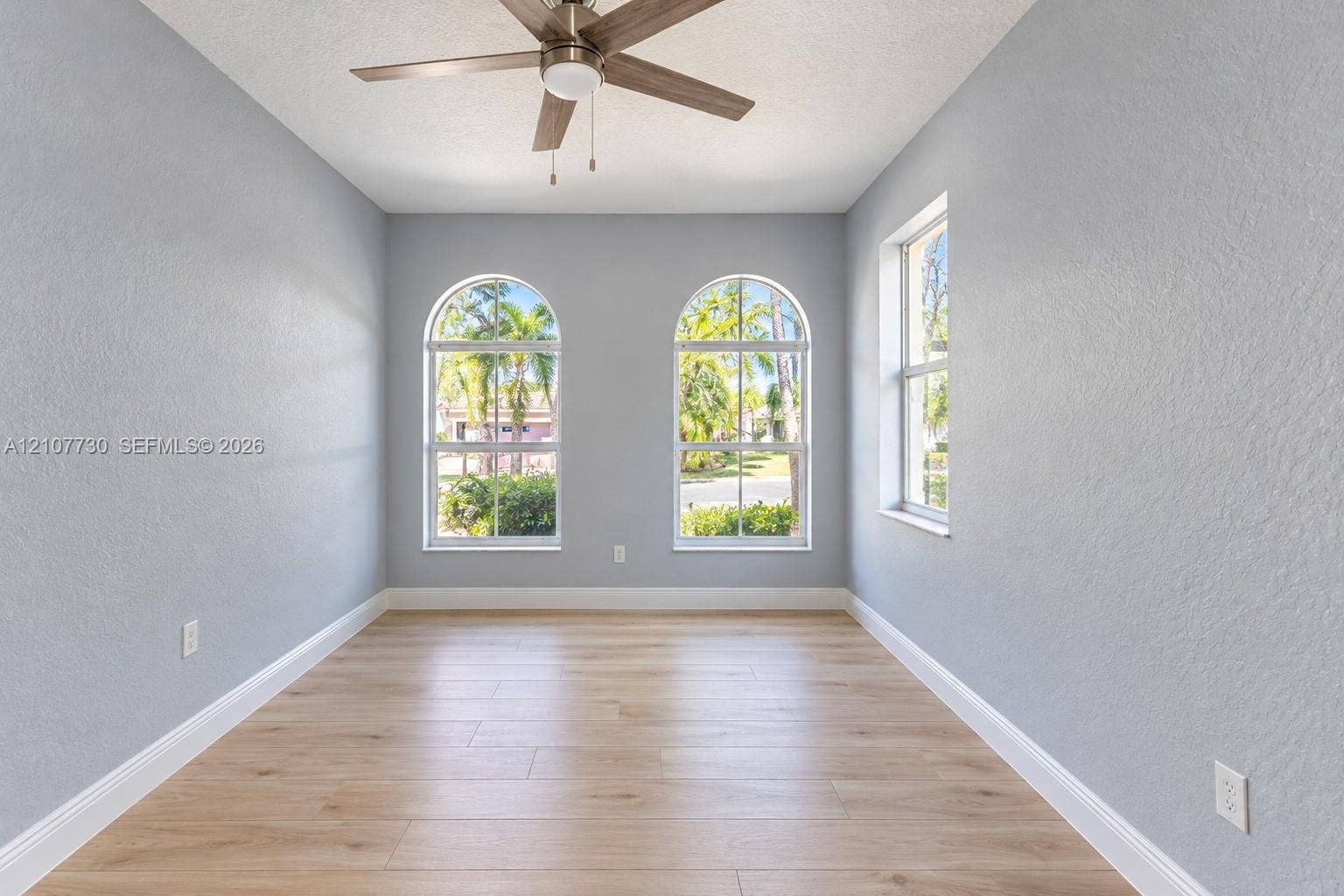 15606 SW 52nd Court, Miramar, FL 33027 Room featuring wood-finish flooring, two arched windows, a single rectangular window, and a ceiling fan