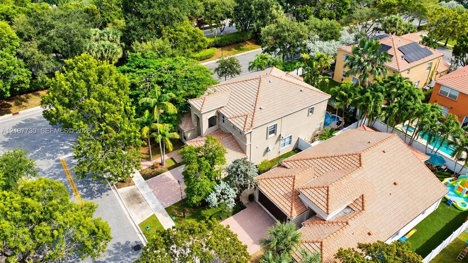 15606 SW 52nd Court, Miramar, FL 33027 Aerial perspective of a multi-story residence featuring a clay tile roof, paved driveway, integrated garage, and mature landscaping