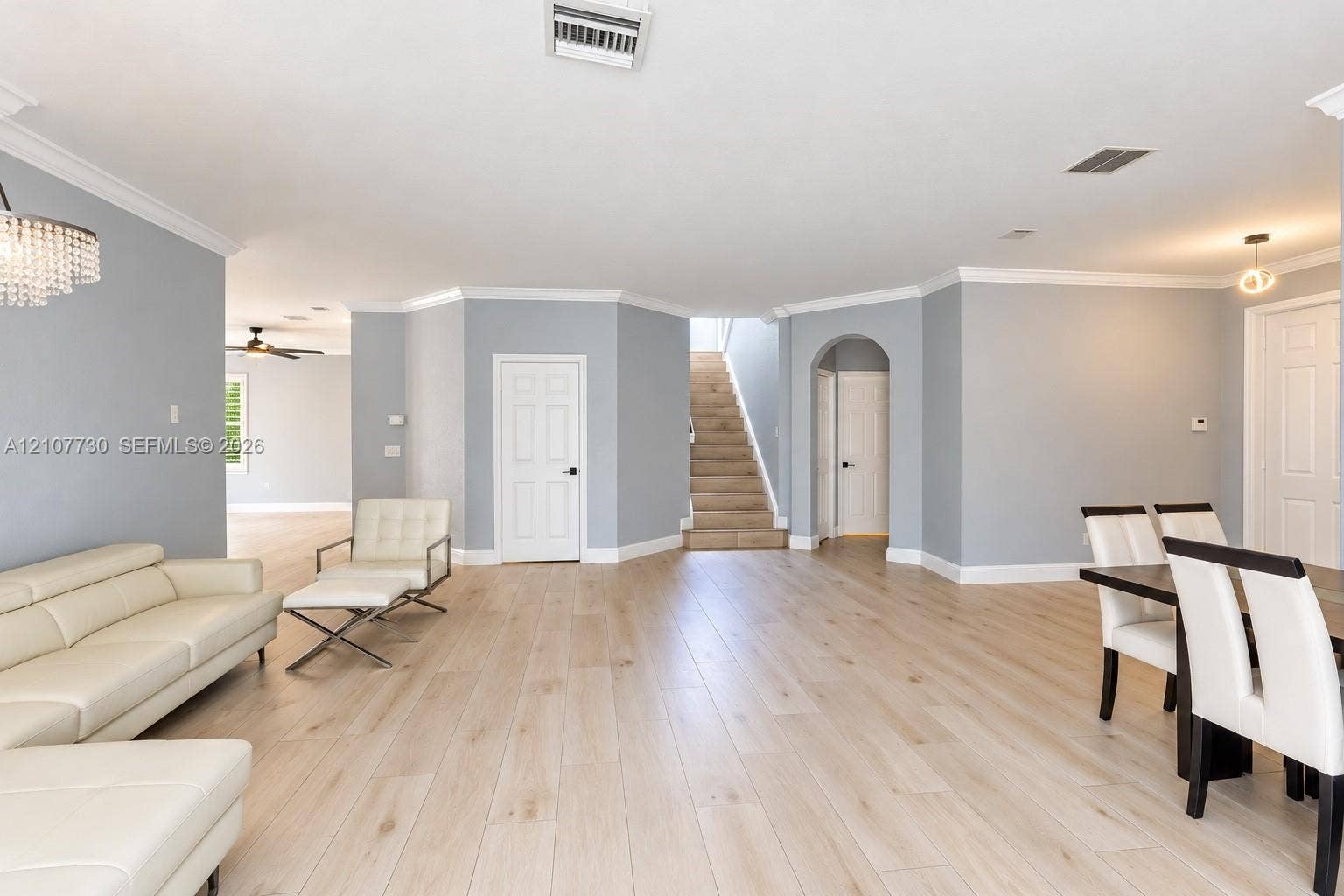 15606 SW 52nd Court, Miramar, FL 33027 Open-concept interior featuring light wood-finish flooring, crown molding, arched architectural detailing, and a multi-level staircase with carpeted treads
