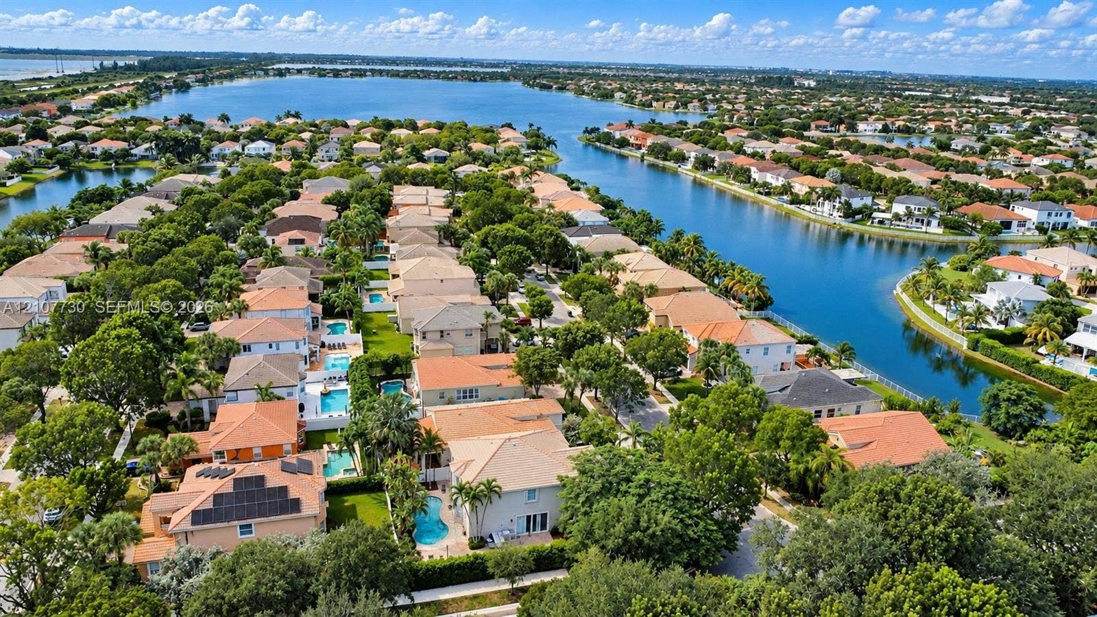 15606 SW 52nd Court, Miramar, FL 33027 Aerial perspective of a residential neighborhood featuring waterfront positioning, tile roof architecture, backyard swimming pools, solar panel installations, and mature landscaping