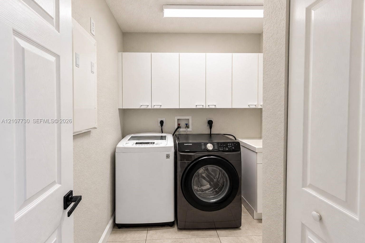15606 SW 52nd Court, Miramar, FL 33027 Laundry room featuring white shaker-style wall-mounted cabinetry, tile flooring, and a dedicated utility sink