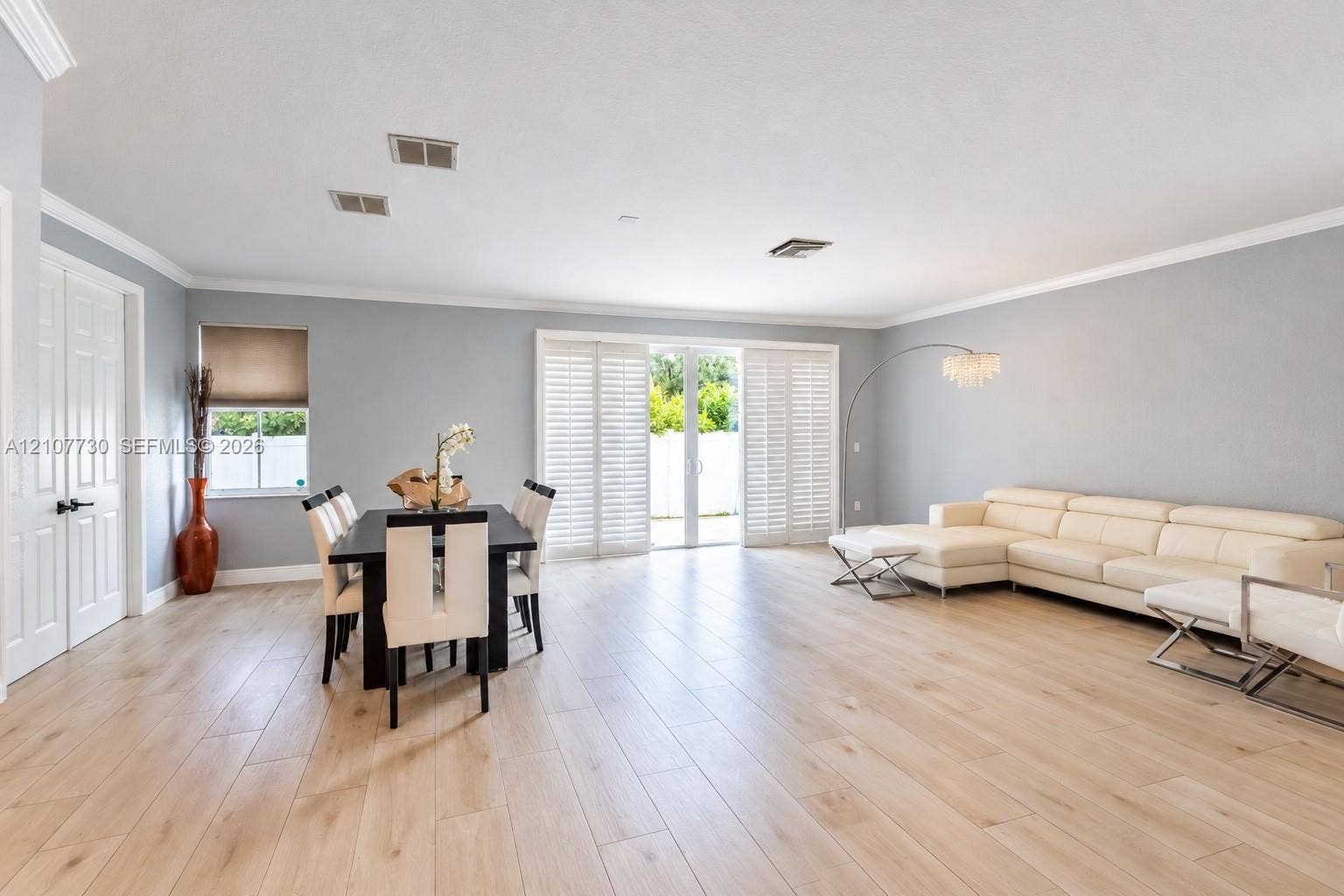 15606 SW 52nd Court, Miramar, FL 33027 Open-concept floor plan featuring wood-finish flooring, crown molding, sliding glass doors with plantation shutters, and recessed lighting