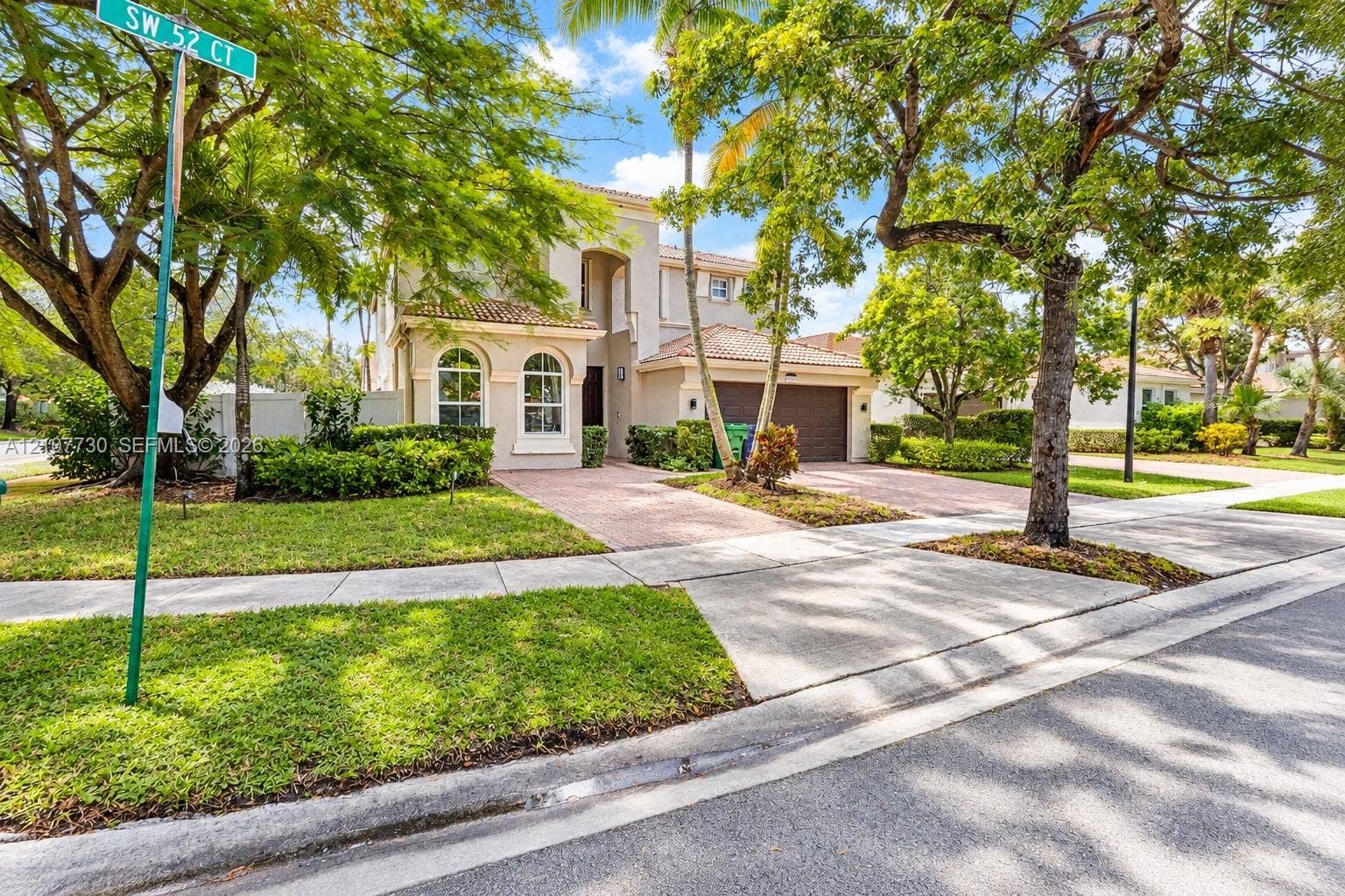 15606 SW 52nd Court, Miramar, FL 33027 Two-story residence featuring a tile roof, arched windows, concrete paver driveway, and mature landscaping