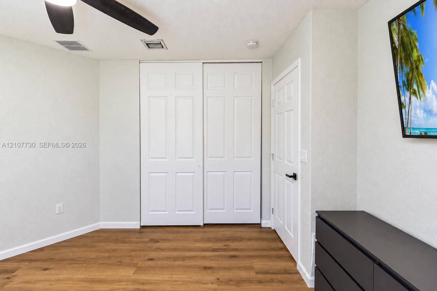 15606 SW 52nd Court, Miramar, FL 33027 Neutral-toned interior featuring wood-finish flooring, sliding dual-panel closet doors, and a ceiling fan with integrated lighting