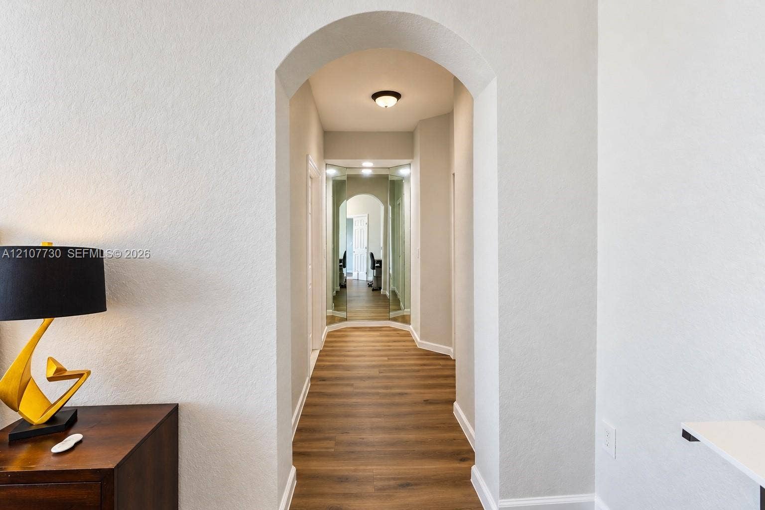 15606 SW 52nd Court, Miramar, FL 33027 Arched doorway featuring wood-finish flooring, neutral wall paint, and mirrored wall panels