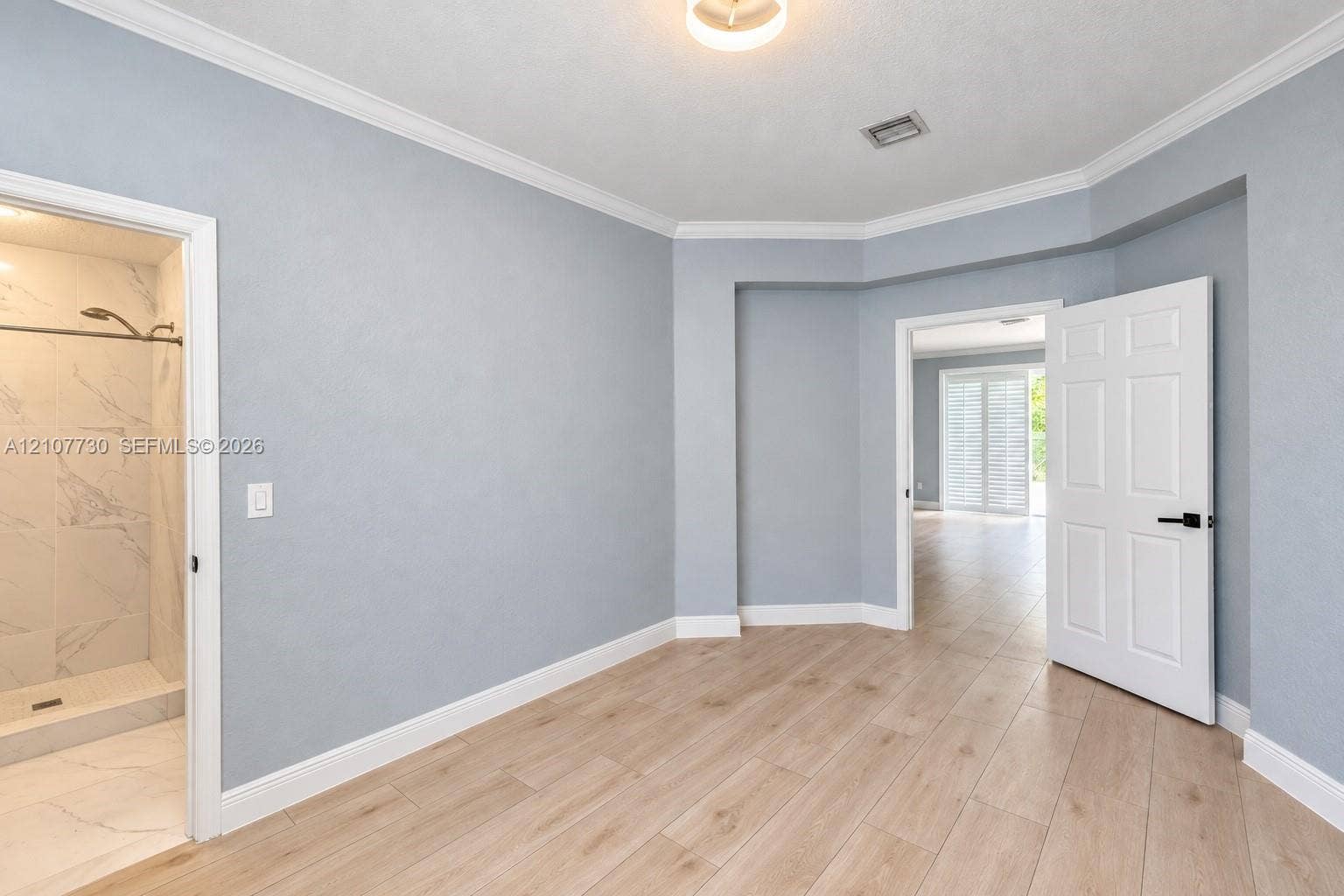 15606 SW 52nd Court, Miramar, FL 33027 Room featuring wood-finish tile flooring, crown molding, multi-panel doors with matte black hardware, and an en-suite with stone-finish wall tile and a walk-in shower