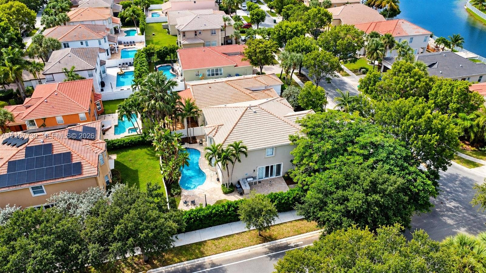 15606 SW 52nd Court, Miramar, FL 33027 Aerial perspective of a two-story residence featuring a tile roof, an in-ground swimming pool, stone-paver patio, and mature landscaping