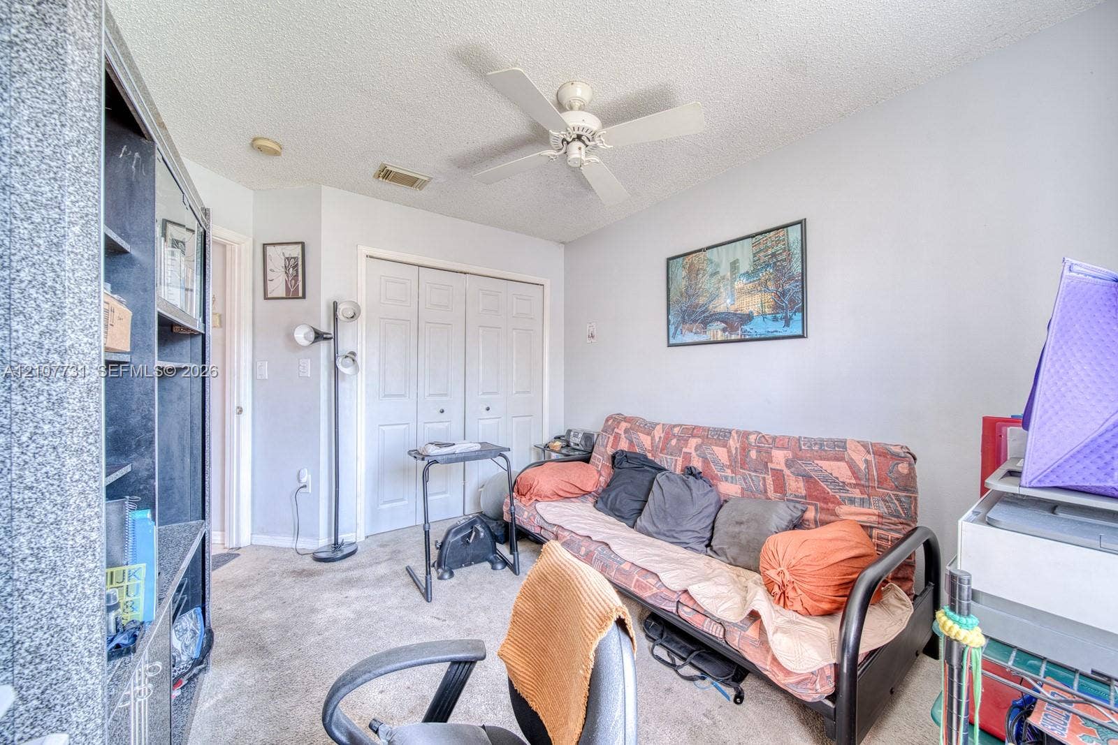 Room featuring a ceiling fan, wall-to-wall carpeting, and double-door closet cabinetry