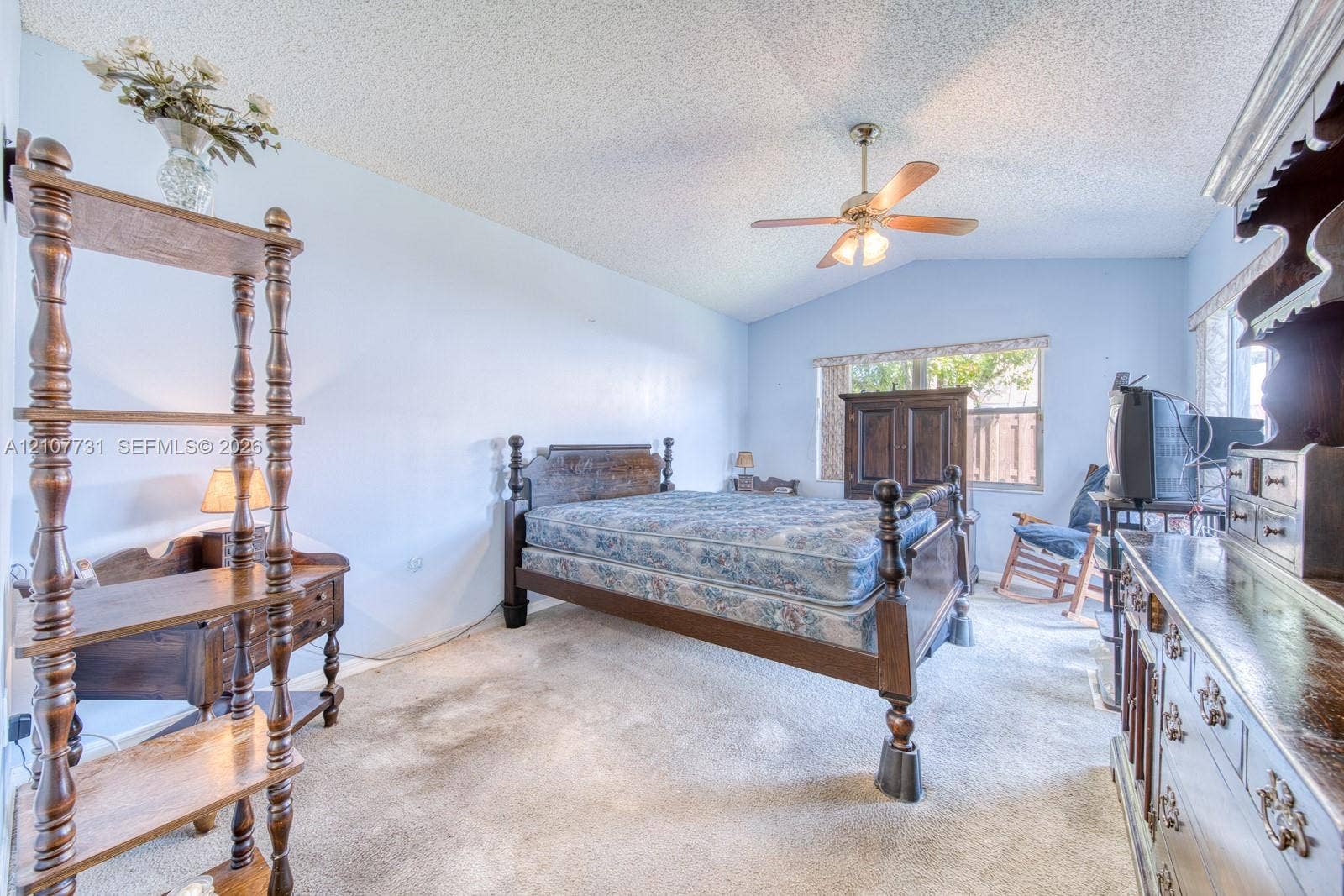 Vaulted ceilings, neutral carpeting, and a central ceiling fan