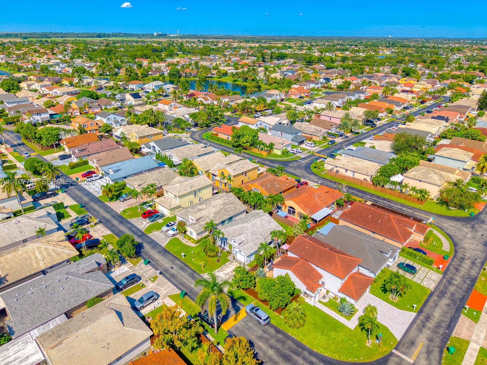 Aerial perspective of a residential community featuring curvilinear street layouts, established landscaping, dense greenery, and concrete paved driveways