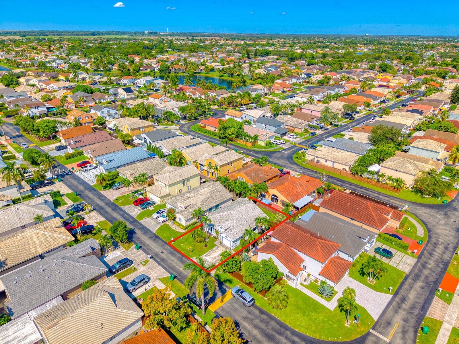 Aerial perspective of a single-story residence featuring a concrete tile roof, attached garage, paved driveway, and landscaped front yard