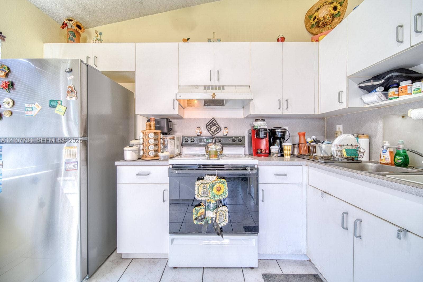 Kitchen featuring white cabinetry, stainless steel refrigerator, white electric range, integrated range hood, and tile flooring