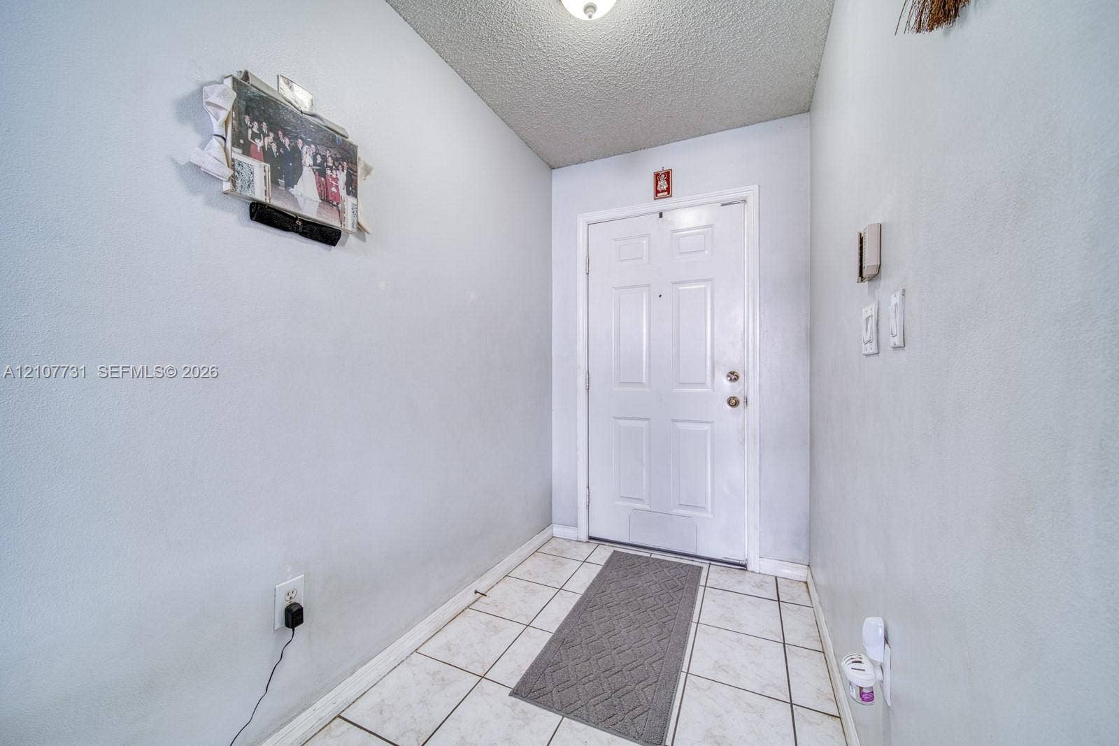 Entryway featuring tile flooring, a six-panel exterior door, and a textured ceiling finish