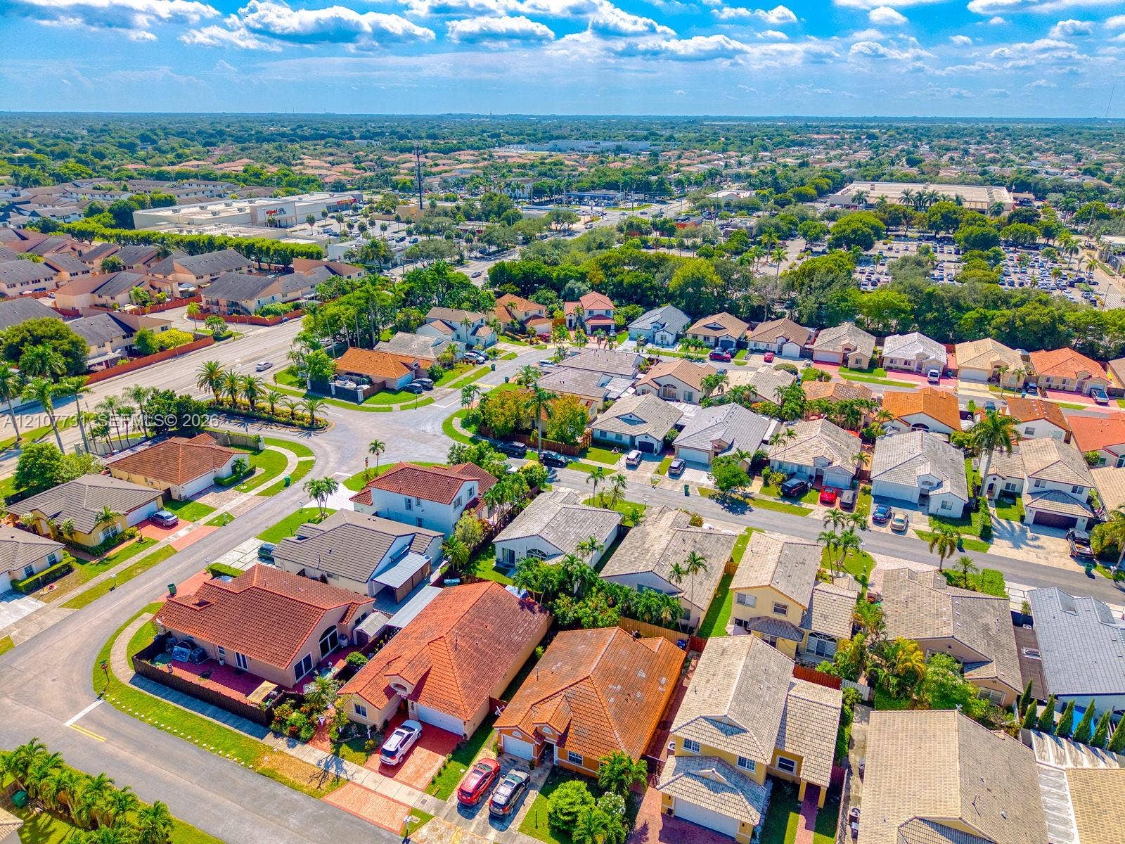 Aerial perspective of a suburban neighborhood featuring paved streets, varied rooflines, mature landscaping, and multi-parcel residential layout