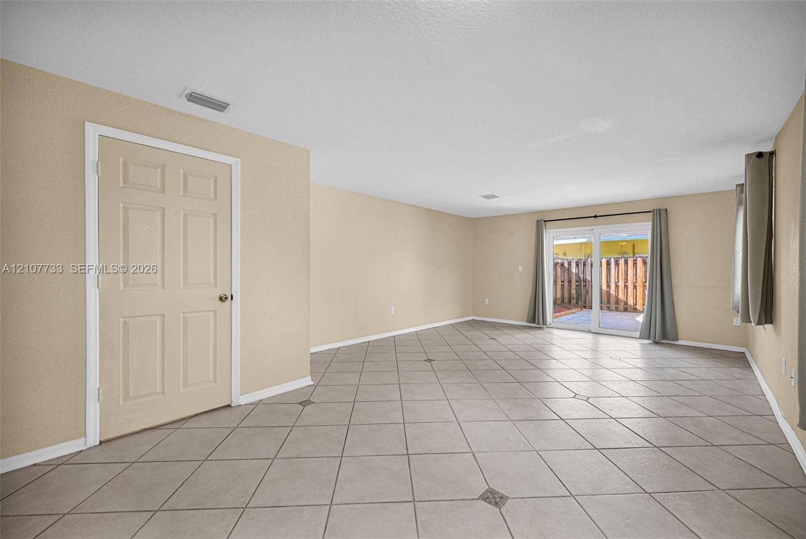 19606 SW 103rd Court, #4, Cutler Bay, FL 33157 Interior space featuring large-format ceramic tile flooring with decorative stone accents, neutral-toned walls, and sliding glass doors with direct exterior access