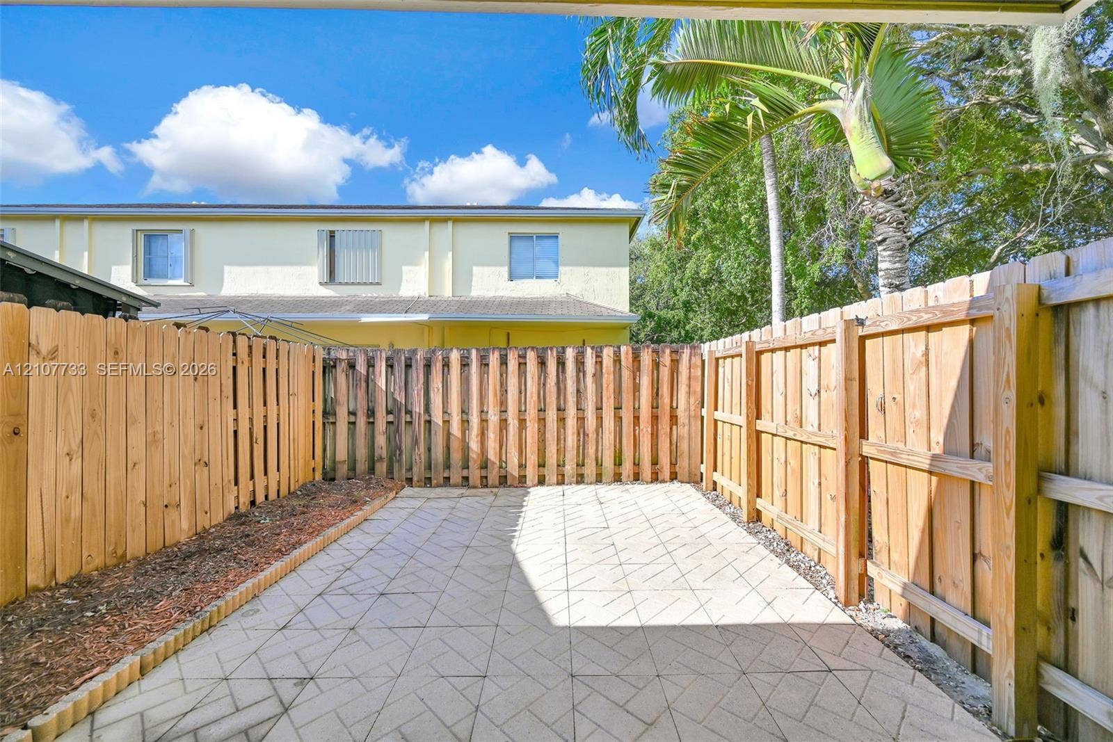 19606 SW 103rd Court, #4, Cutler Bay, FL 33157 Private patio featuring patterned concrete pavers and enclosed by a wood-slat privacy fence