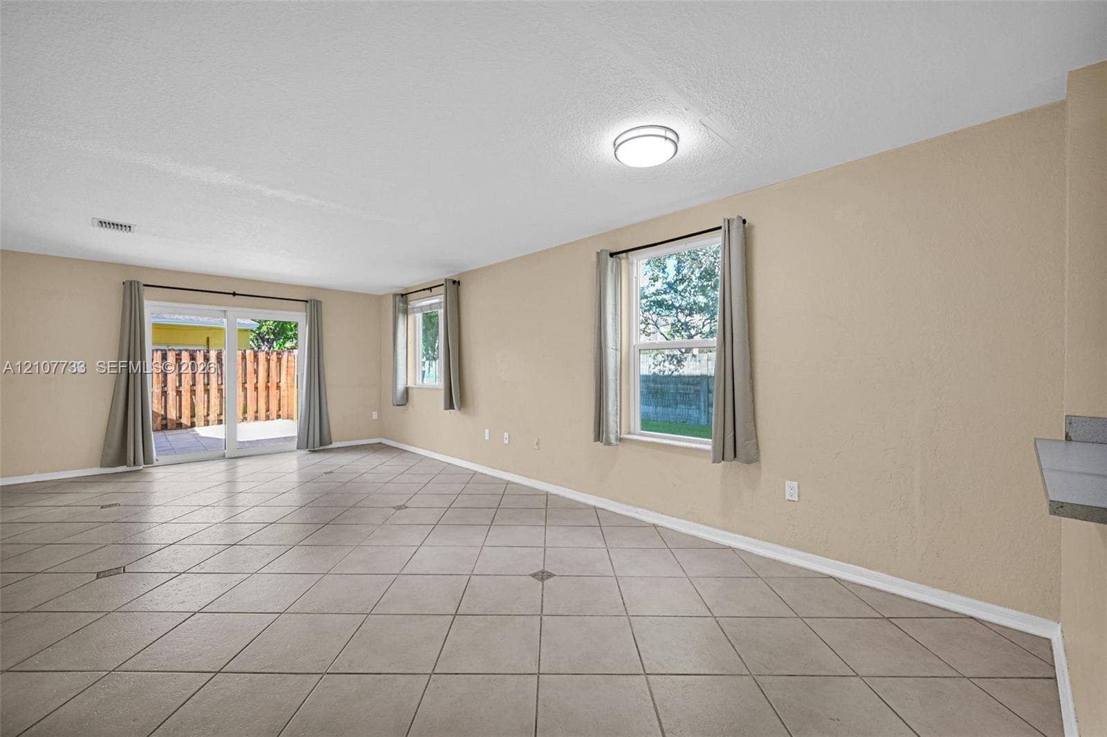 19606 SW 103rd Court, #4, Cutler Bay, FL 33157 Open-concept interior featuring neutral wall tones, large-format tile flooring, dual-pane windows, and sliding glass doors with exterior access