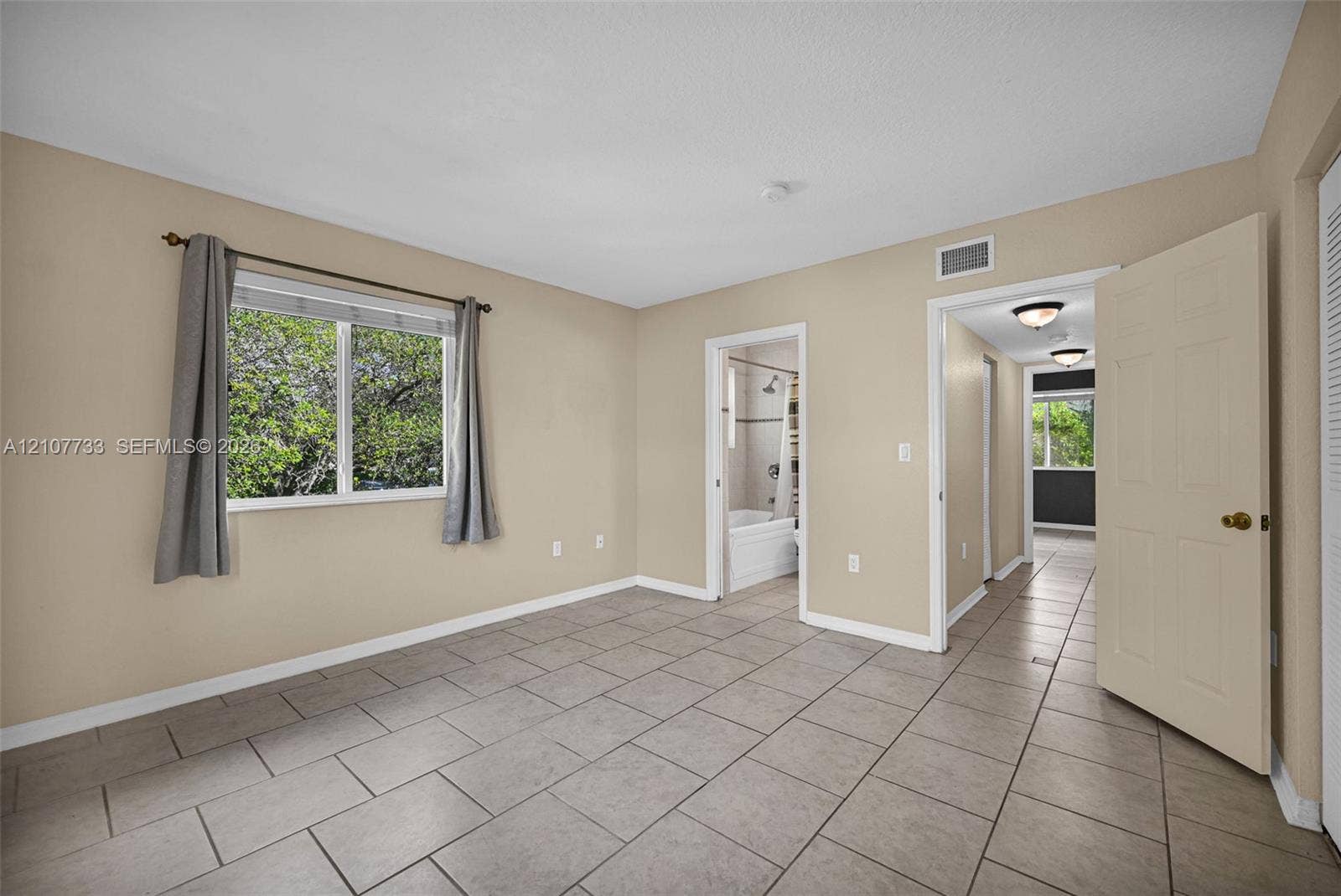 19606 SW 103rd Court, #4, Cutler Bay, FL 33157 Neutral-toned room featuring rectangular tile flooring, a horizontal sliding window, and interior paneled doors