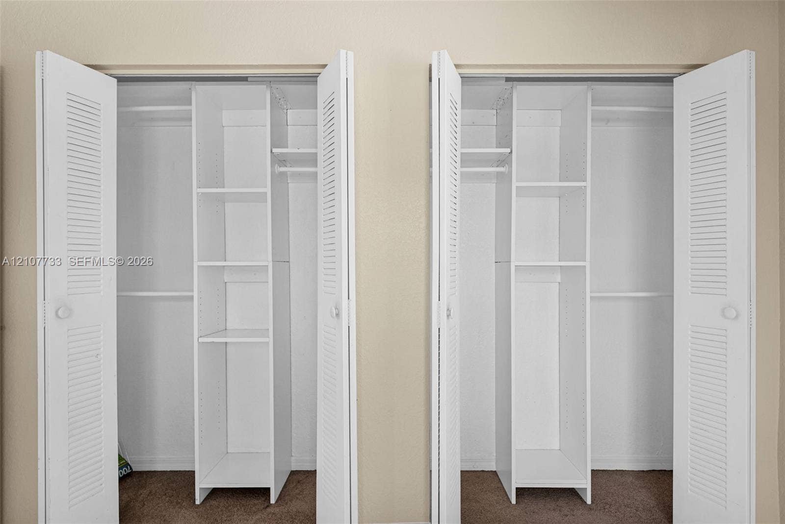 19606 SW 103rd Court, #4, Cutler Bay, FL 33157 Dual closets featuring white louvered doors, built-in shelving towers, and integrated hanging rods