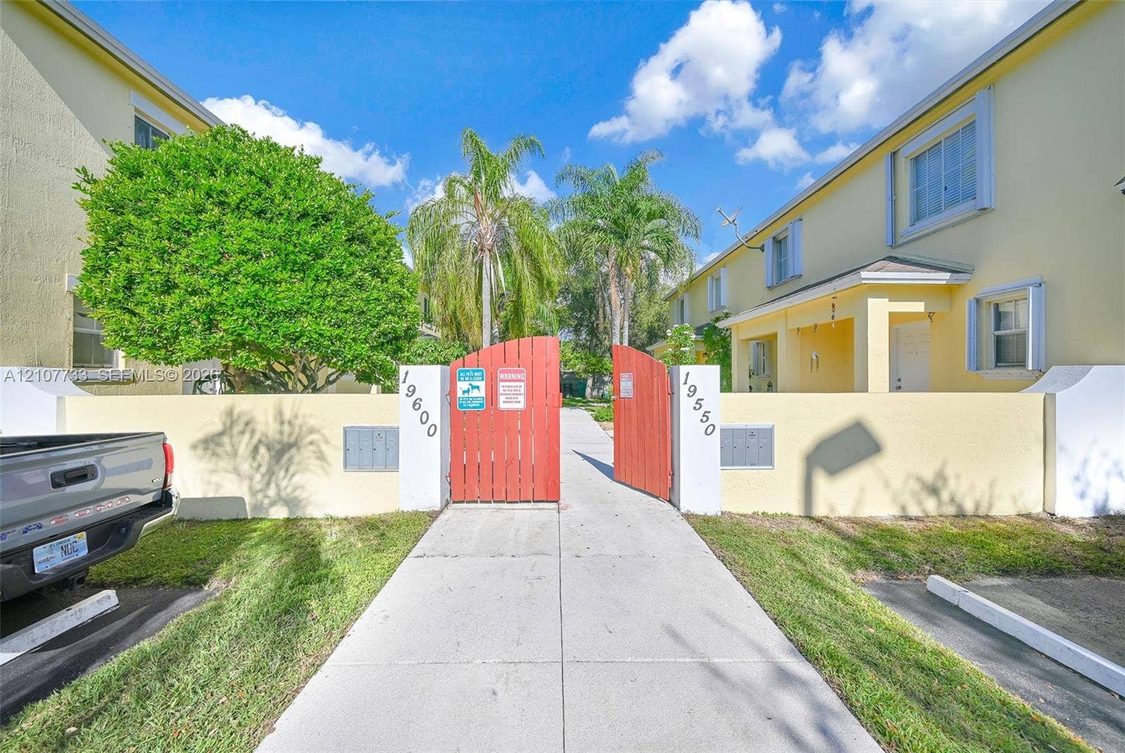19606 SW 103rd Court, #4, Cutler Bay, FL 33157 Stucco exterior buildings with a gated entry, concrete walkway, and palm tree landscaping