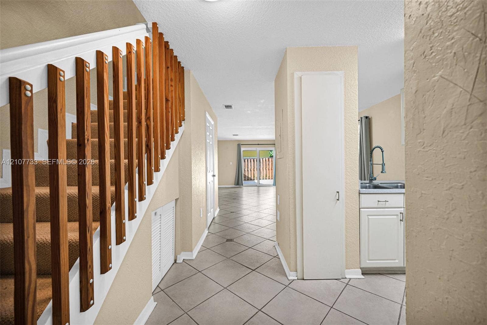 19606 SW 103rd Court, #4, Cutler Bay, FL 33157 Interior area featuring ceramic tile flooring, staircase with vertical wood balusters, built-in floor-to-ceiling cabinetry, and a kitchenette area with a stainless steel sink and white cabinetry