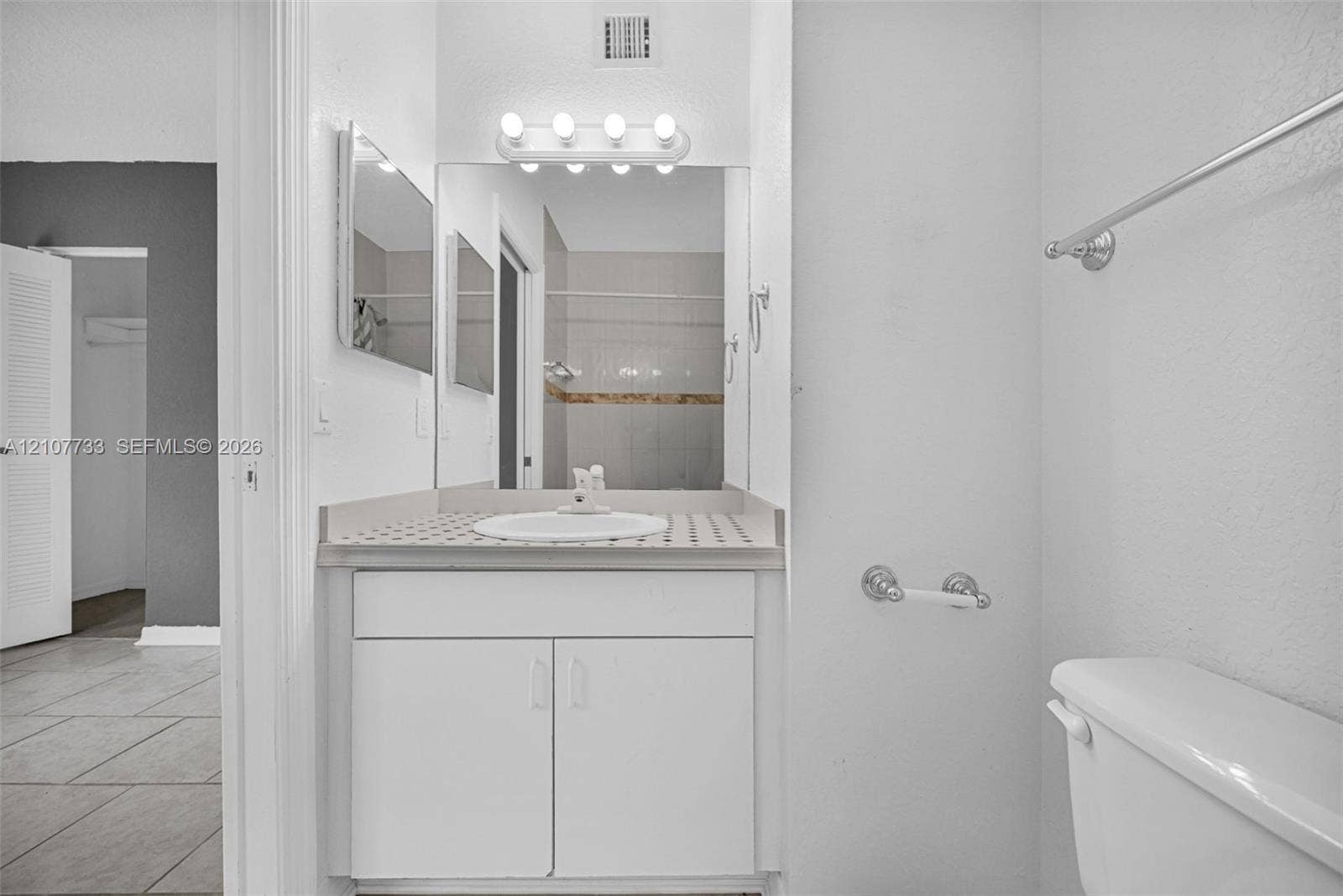 19606 SW 103rd Court, #4, Cutler Bay, FL 33157 Bathroom featuring a vanity with a circular drop-in sink, tiled countertop, five-light wall-mounted vanity fixture, and large square mirror