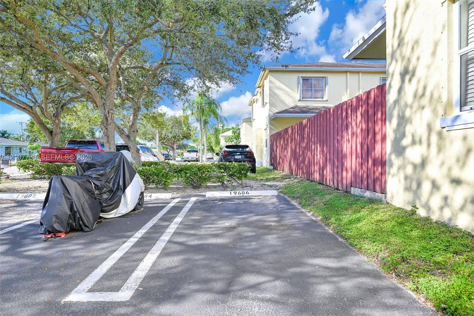 19606 SW 103rd Court, #4, Cutler Bay, FL 33157 Asphalt-paved parking area featuring designated spaces, stucco exterior walls, and privacy fencing