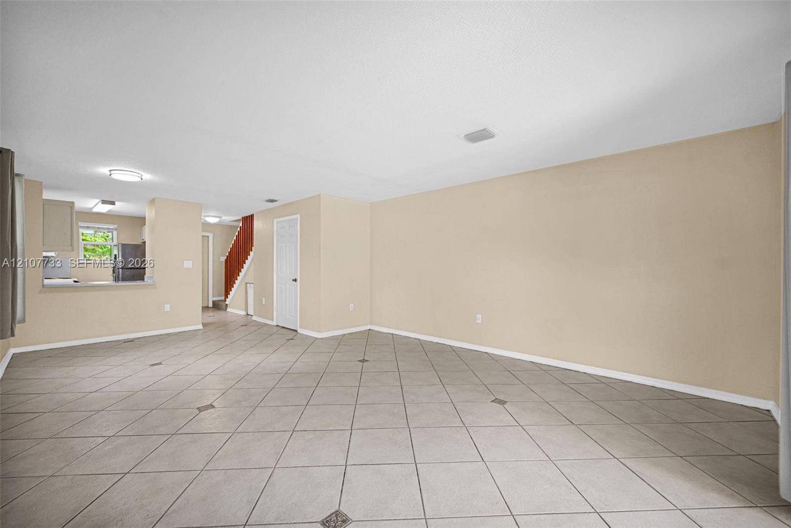 19606 SW 103rd Court, #4, Cutler Bay, FL 33157 Open-concept interior featuring large-format diagonal tile flooring with decorative inlay accents, neutral wall tones, recessed ceiling lighting, and a built-in staircase with a wood-finish handrail