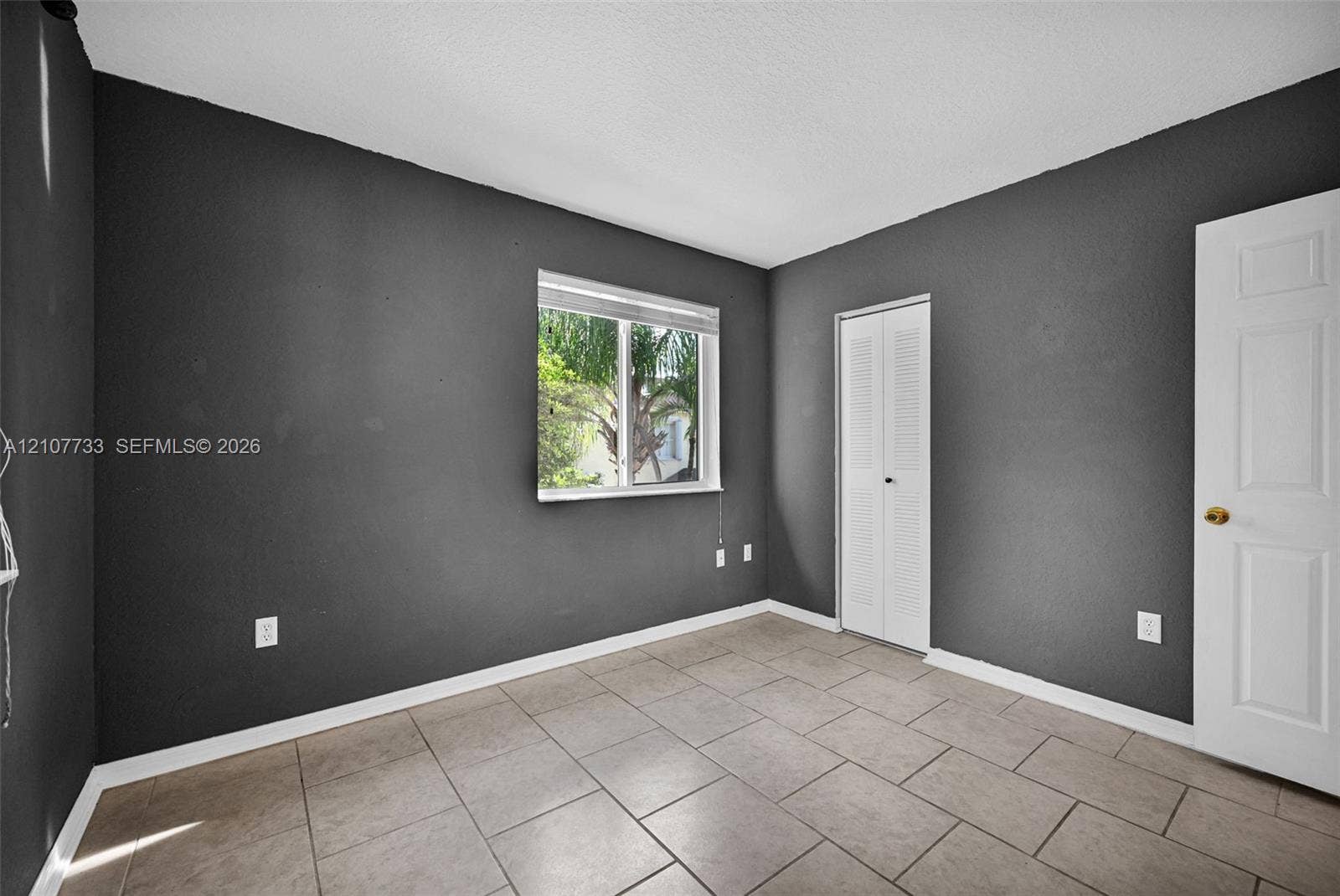 19606 SW 103rd Court, #4, Cutler Bay, FL 33157 Room featuring tile flooring, neutral painted walls, a sliding louvered closet door, and a single-pane window