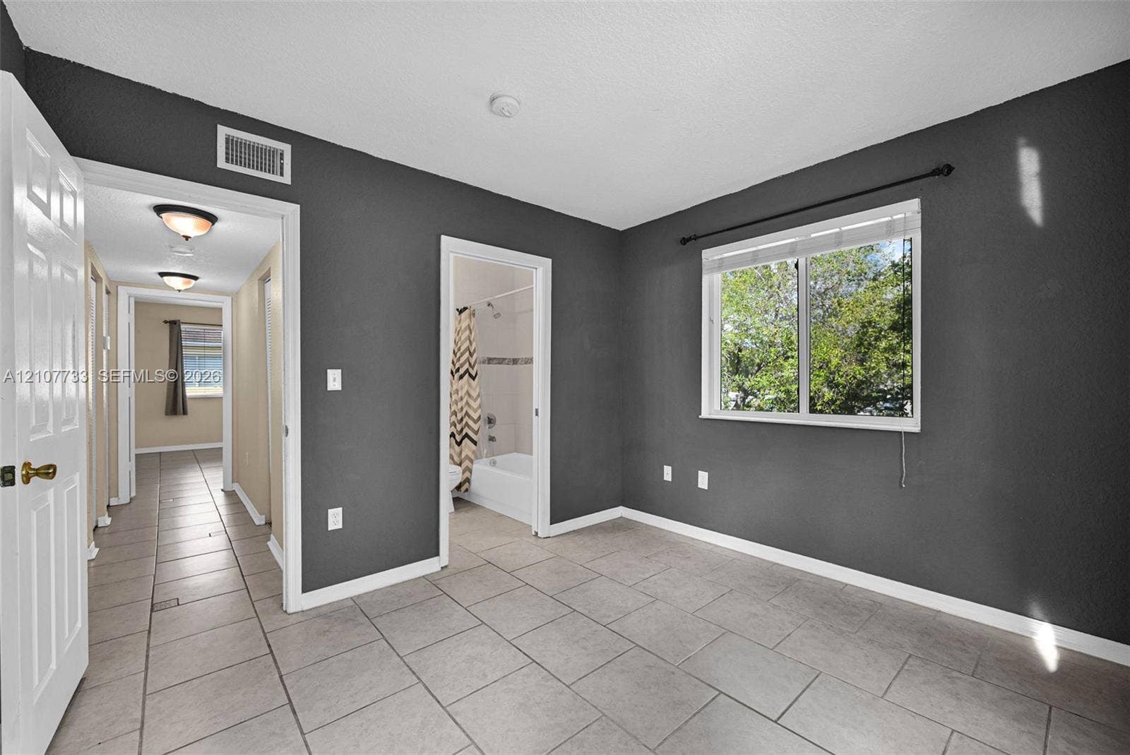 19606 SW 103rd Court, #4, Cutler Bay, FL 33157 Room featuring large-format ceramic tile flooring, a single-pane window with white trim, and neutral wall tones
