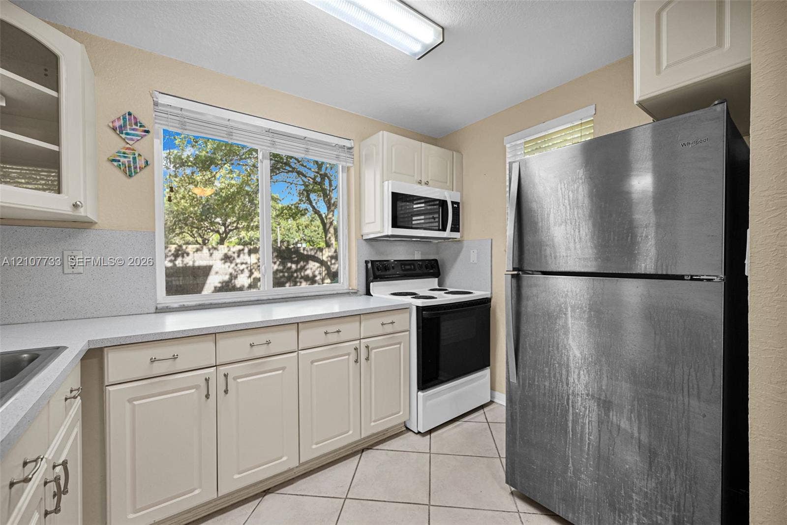 19606 SW 103rd Court, #4, Cutler Bay, FL 33157 Kitchen featuring off-white cabinetry, solid surface countertops, a stainless steel refrigerator, white electric range, and tile flooring