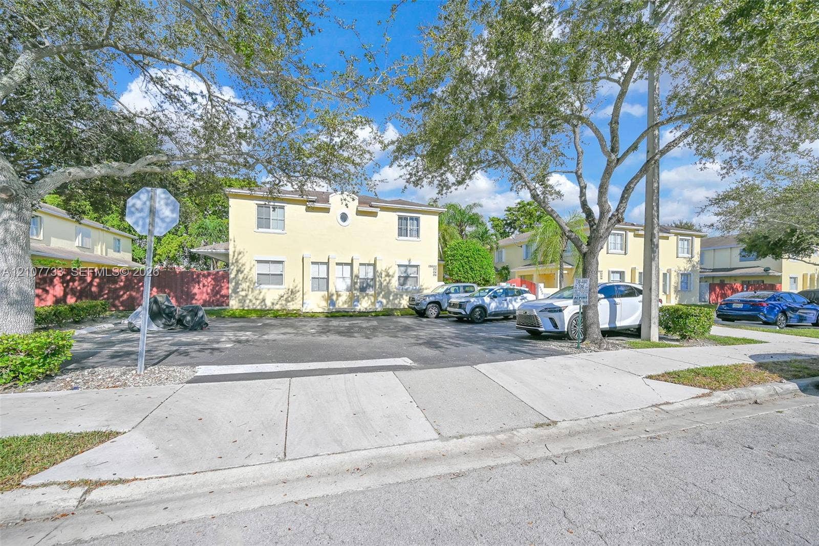 19606 SW 103rd Court, #4, Cutler Bay, FL 33157 Stucco exterior building featuring a decorative oculus window, mature shade trees, and an asphalt parking lot