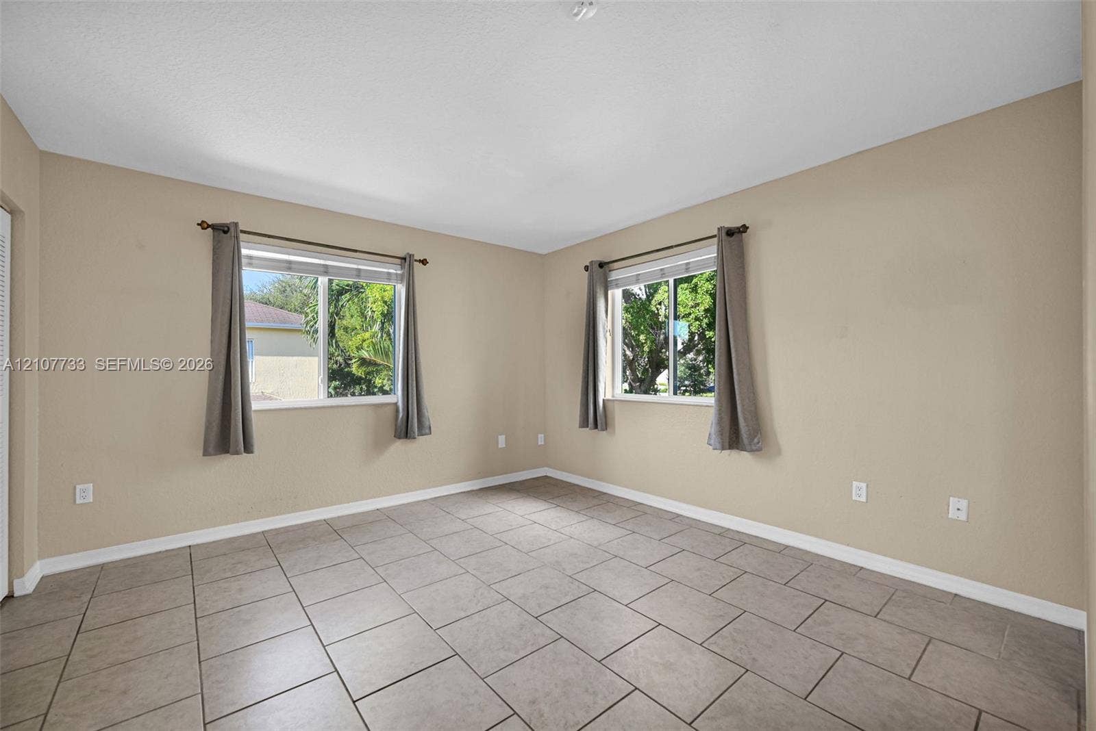 19606 SW 103rd Court, #4, Cutler Bay, FL 33157 Neutral-toned interior featuring large-format ceramic tile flooring, dual windows with double-track hardware, and textured ceiling finish