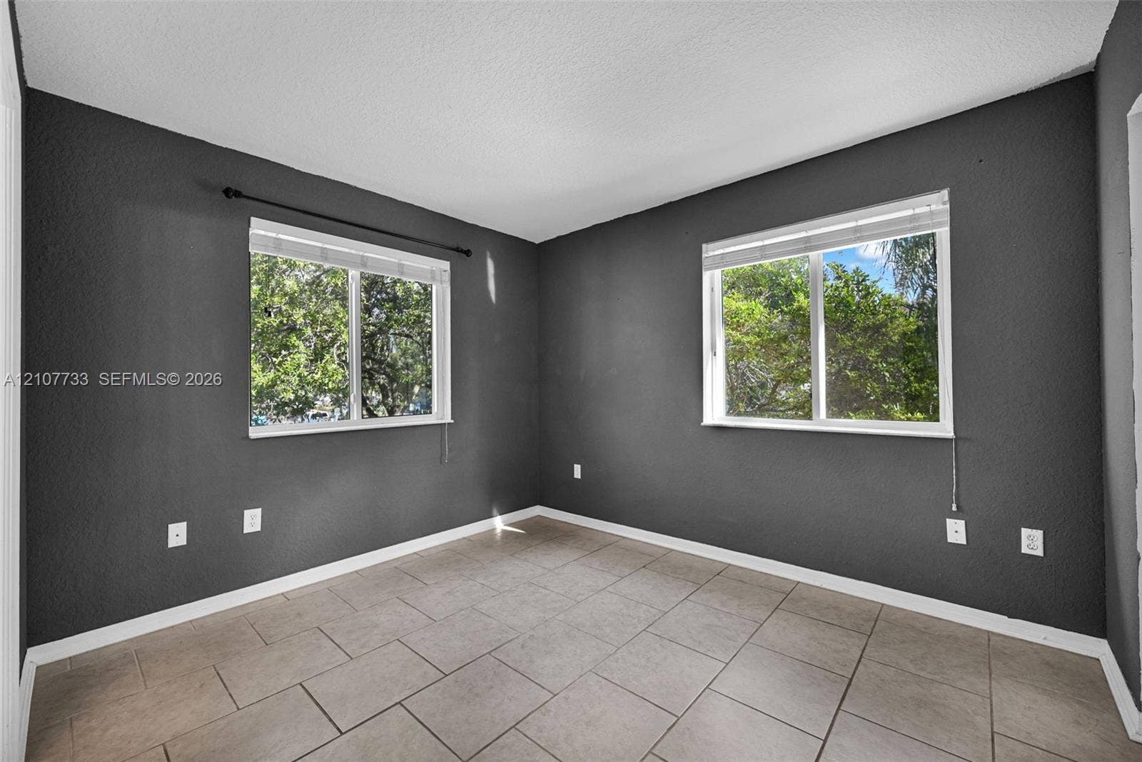 19606 SW 103rd Court, #4, Cutler Bay, FL 33157 Room featuring dark-toned walls, tile flooring, and two windows with horizontal blinds