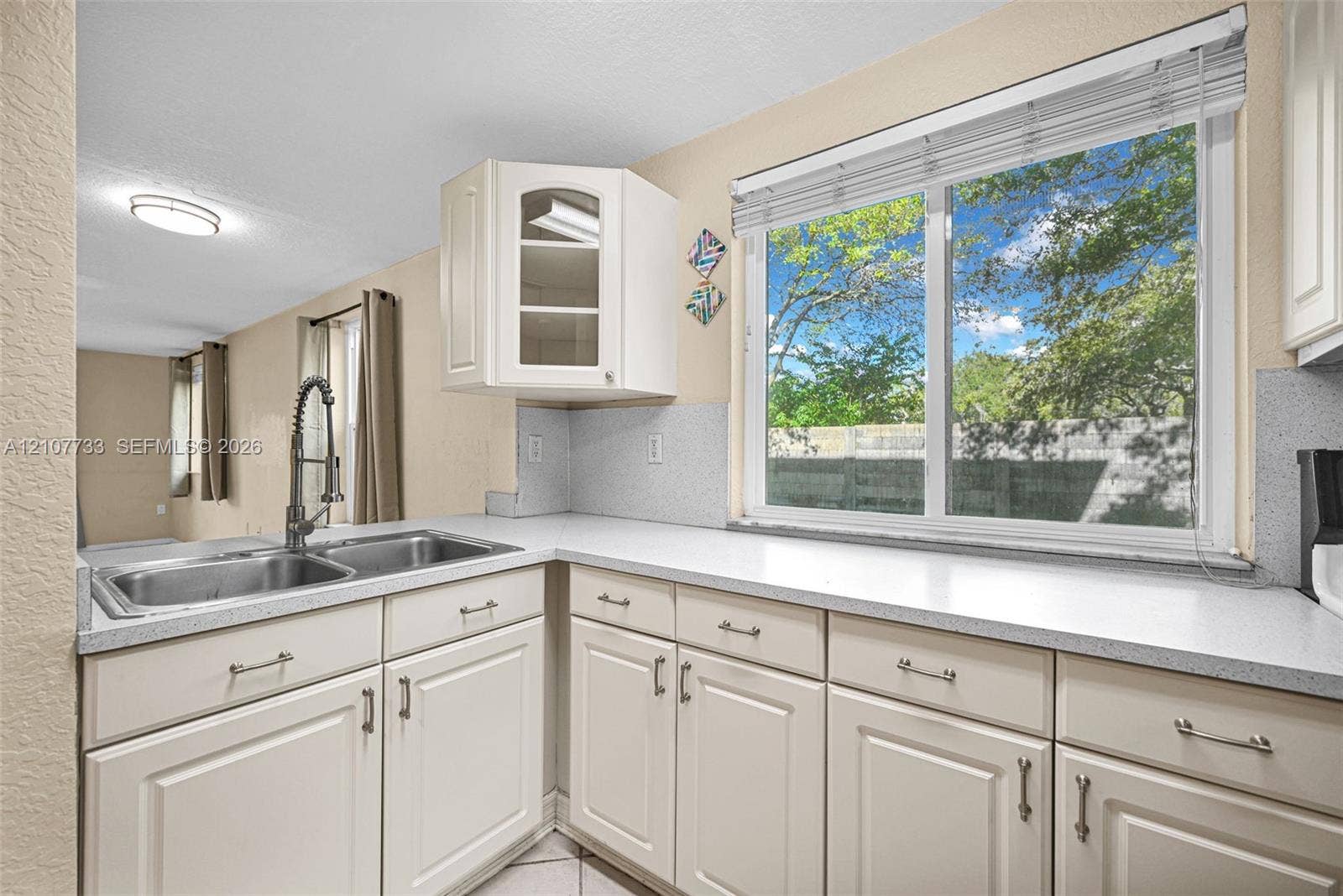 19606 SW 103rd Court, #4, Cutler Bay, FL 33157 Kitchen featuring white cabinetry, solid-surface countertops, dual-basin stainless steel sink with pull-down faucet, and a large window