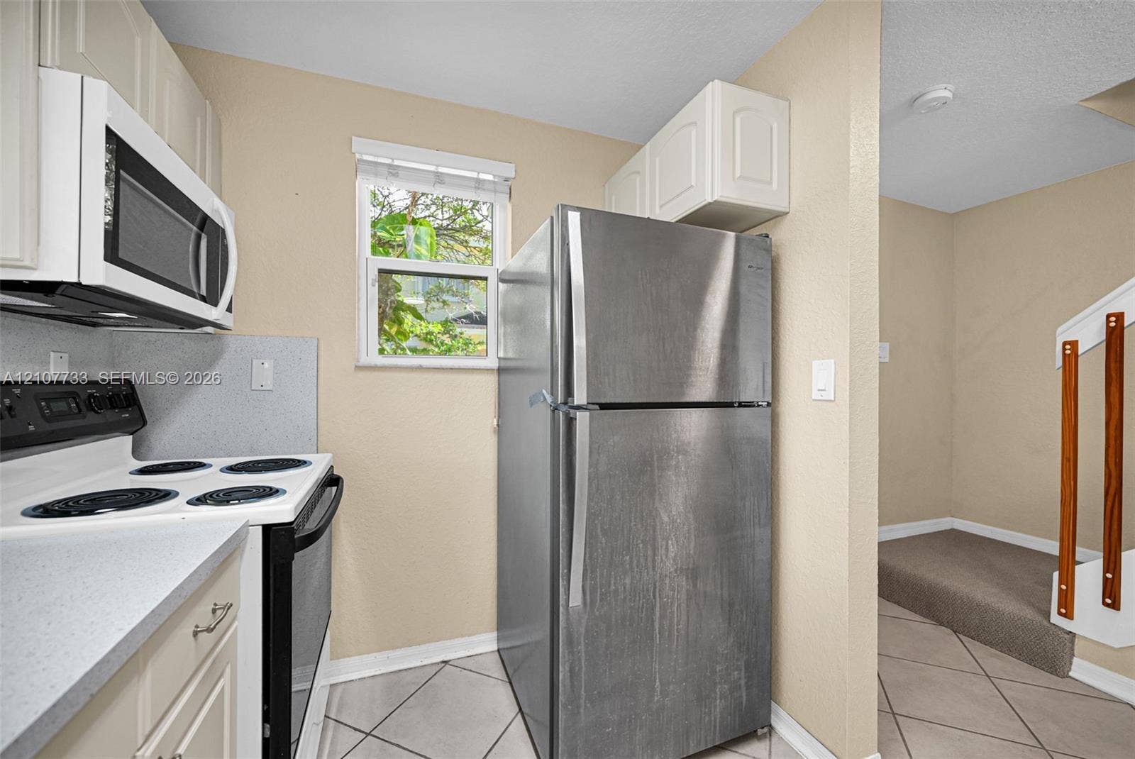 19606 SW 103rd Court, #4, Cutler Bay, FL 33157 Kitchen featuring white cabinetry, solid-surface countertops, stainless steel refrigerator, white electric range, and ceramic tile flooring