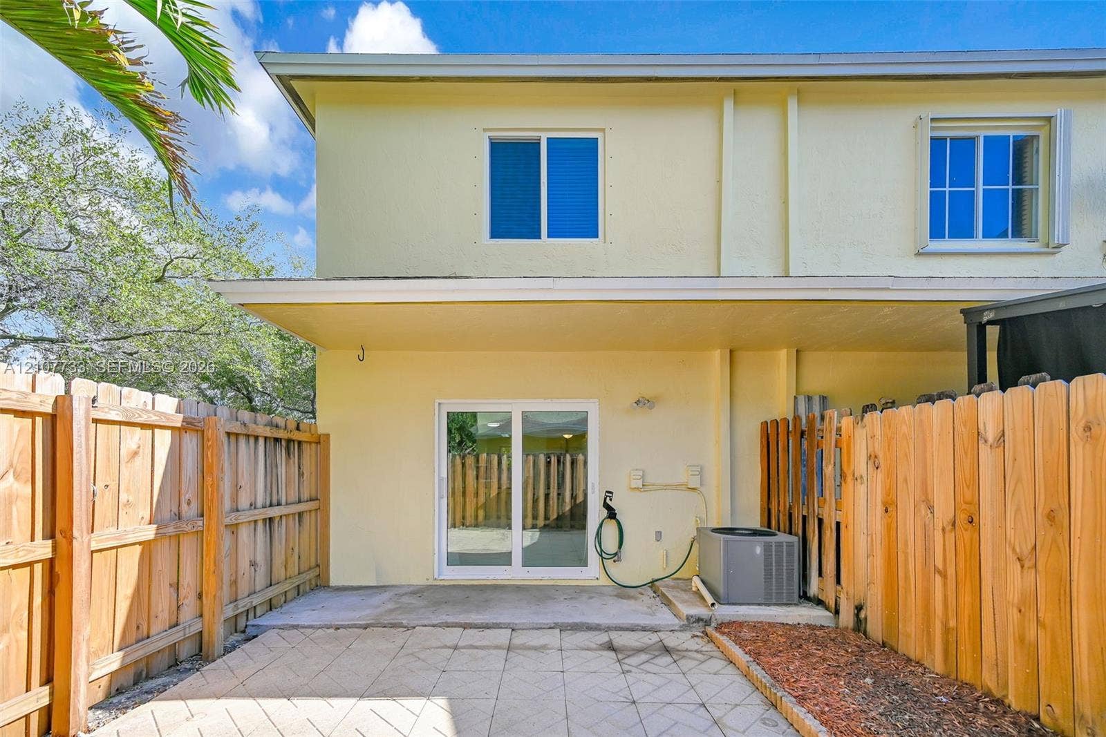 19606 SW 103rd Court, #4, Cutler Bay, FL 33157 Rear exterior featuring a concrete patio, sliding glass doors, and a wood privacy fence