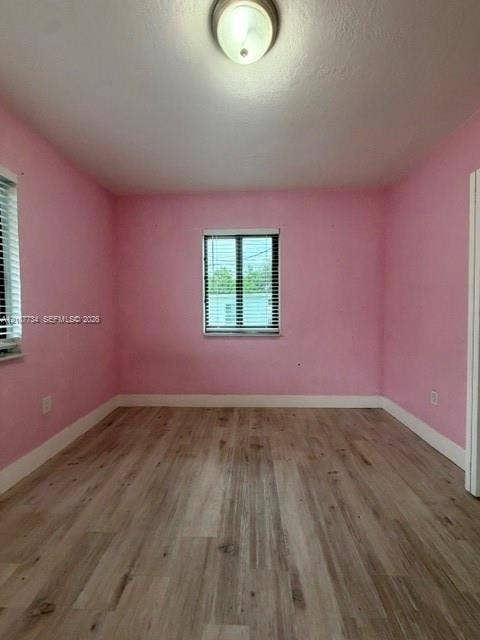 Room featuring wood-finish flooring, dual windows with horizontal blinds, and a flush-mount ceiling light fixture