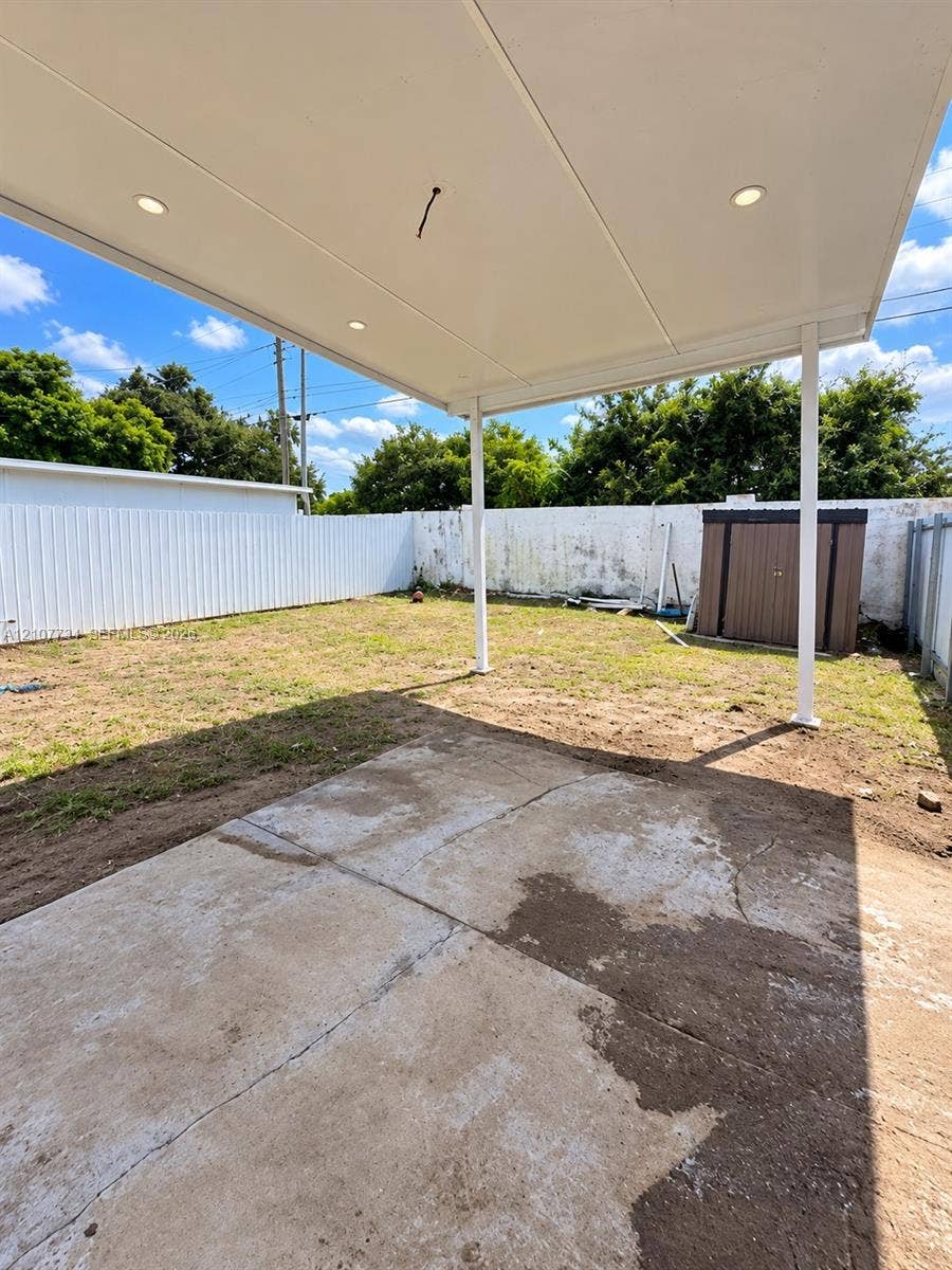Covered patio featuring a concrete slab and recessed lighting, set within a fenced backyard