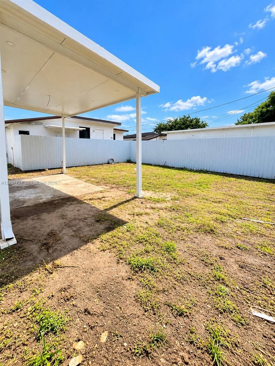 Covered concrete patio with recessed lighting and a full-perimeter white privacy fence