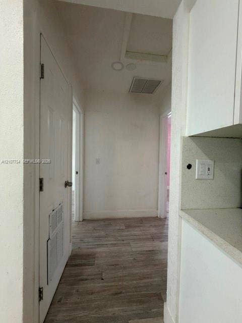 Interior hallway featuring wood-finish flooring, white cabinetry, solid-surface countertops, and recessed lighting