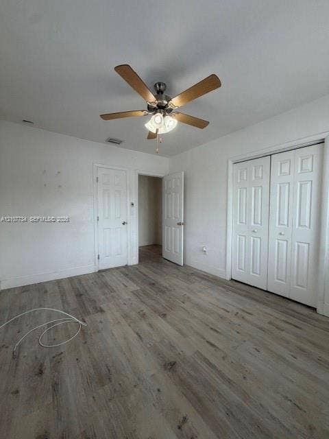 Room featuring wood-finish flooring, a five-blade ceiling fan with integrated lighting, and multi-panel interior doors, including a double-door closet