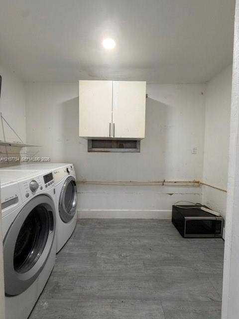 Dedicated laundry room featuring a front-load washer and dryer, abundant cabinetry with stainless steel hardware, concrete flooring, and recessed ceiling lighting for optimal functionality
